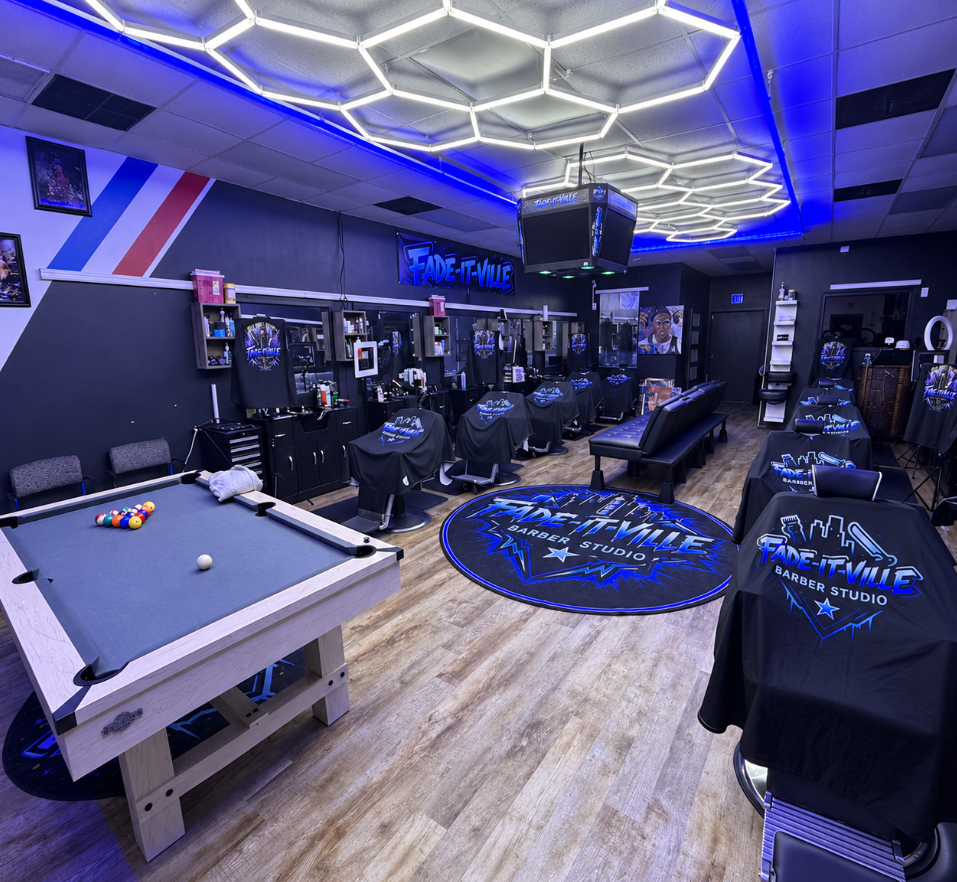 Inside FadeItVille Barber Studio — blue neon hex lights, branded chairs and pool table